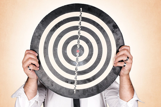 Man holding dartboard on orange background