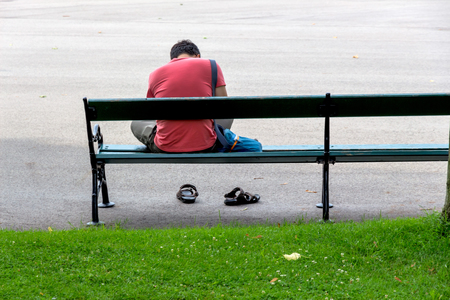 Mann sitzt auf einer Bank, Symbol für Einsamkeit, Depression, Krise