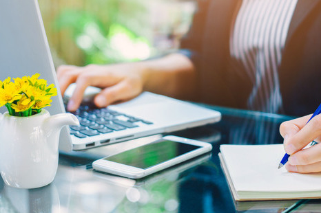 Business woman hand is writing notebook with a pen  and using a laptop computer in the office.Web banner.