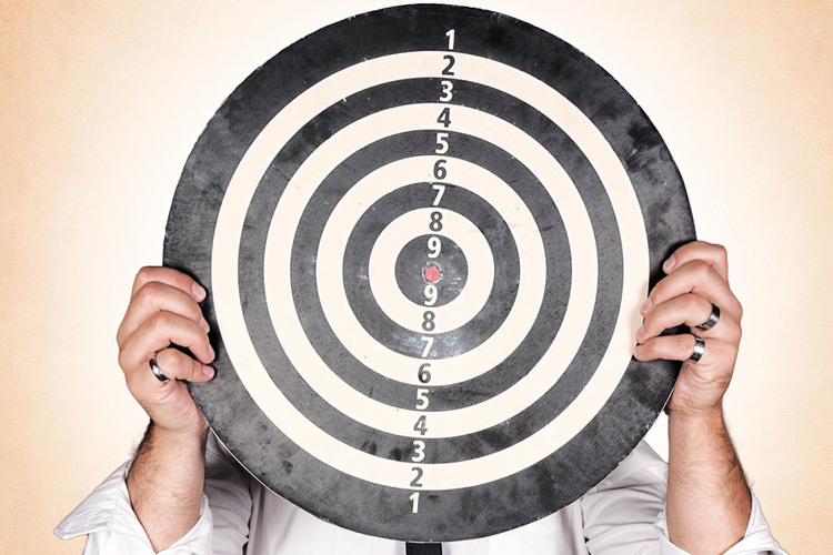 Man holding dartboard on orange background